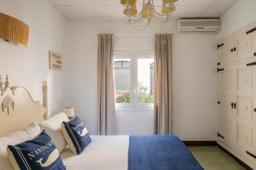 a bedroom with a bed with blue pillows and a window at La Goleta in Llança