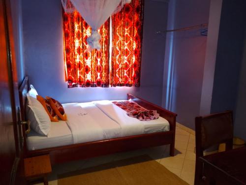 Schlafzimmer mit einem Bett und einem Fenster mit roten Lichtern in der Unterkunft Richy Hotels and Safaris in Mbale