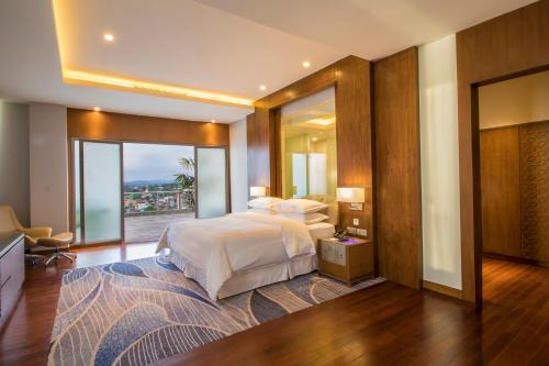 a bedroom with a large bed and a large window at Four Points by Sheraton Manado in Manado