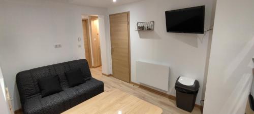 Il comprend un salon doté d'un canapé noir et d'une télévision à écran plat. dans l'établissement AU MENILOIS entre Montagne et Forêt, à Cornimont