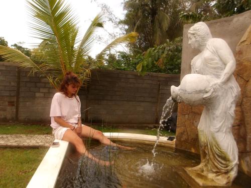 a young girl sitting in a fountain next to a statue at Steps Garden Resort in Negombo