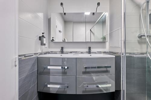 une salle de bain avec un lavabo et un miroir dans l'établissement Le 13 Myosotis - 10min du métro, à Rosny-sous-Bois