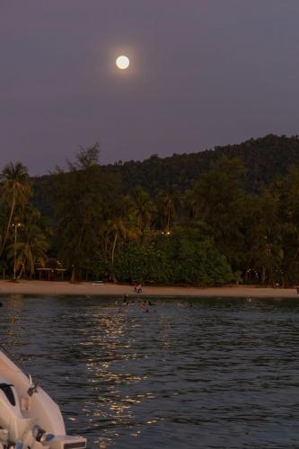 a moon over a beach with a boat in the water at Mafiya Resort in Koh Rong Island