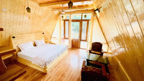 a bedroom with a bed in a room with wooden walls at River Nest Cottage Shangarh in Sainj