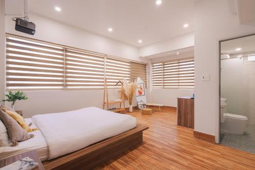 a bedroom with a bed and a desk and some windows at The Morris Central Hotel - O'TEL in Da Lat