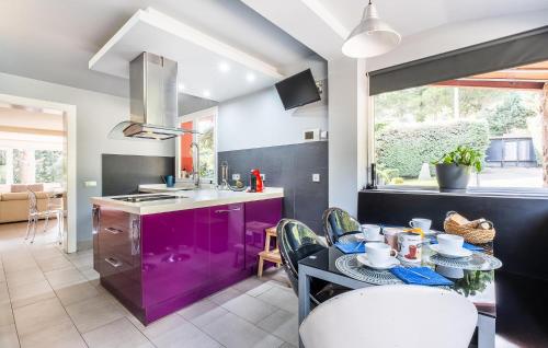 una cocina con armarios morados y una mesa con sillas. en Beautiful Home In Mataelpino, en Mataelpino