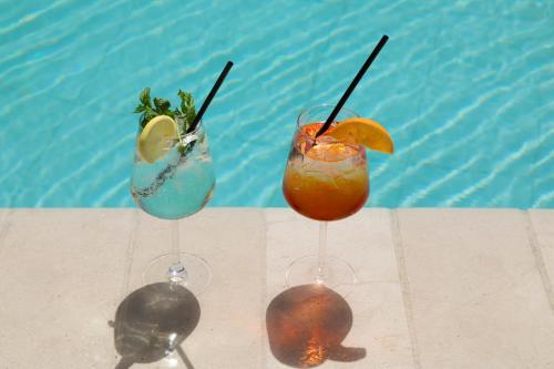 three cocktails sitting on a table next to a pool at Park Hotel Cattolica & Restaurant in Cattolica