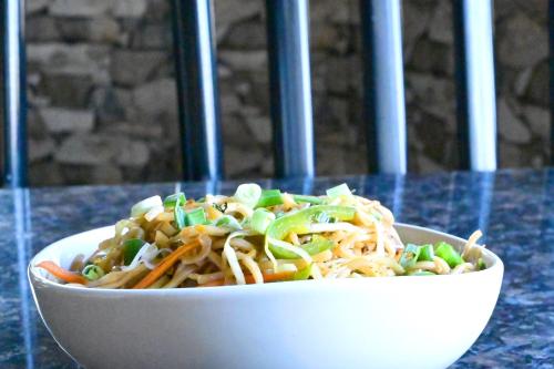 a white bowl of food with noodles and vegetables at Socials by bablos in Molem