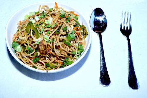 a bowl of noodles and vegetables on a table with a fork at Socials by bablos in Molem