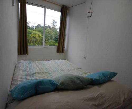 a bed with two pillows in a bedroom with a window at Depto Zona UV Lagos Isleta 102 in Xalapa