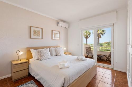a bedroom with a large bed and a balcony at Pool-Golf-Ocean resort home in Praia Del Rey in Amoreira