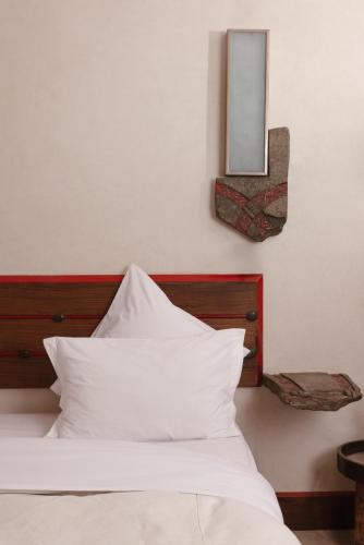 a bed with white pillows and a mirror on the wall at Jnan Lotf Marrakech - Le Jardin de la Bienveillance in Marrakech