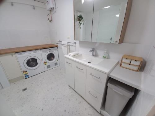 La salle de bains blanche est pourvue d'un lavabo et d'un lave-linge. dans l'établissement NEW Coastal Salty Life - 2 bed 1st Floor, à Perth