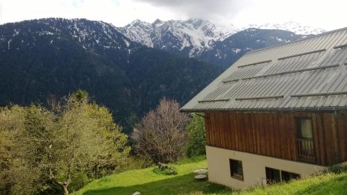 a house on a hill with mountains in the background at Chalet dans les alpages de Savoie in Villard-sur-Doron
