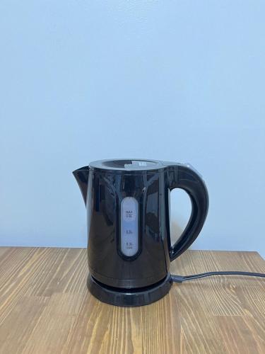 a black coffee pot sitting on a wooden table at YadoPAP Ina town 宿ぱっぷ伊奈町 in Ina