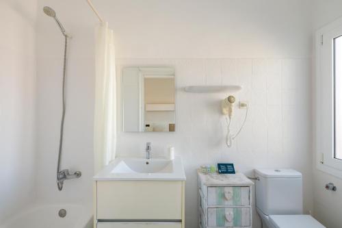 a white bathroom with a sink and a toilet at La Goleta in Llança