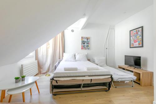 une chambre blanche avec un lit et une télévision dans l'établissement Appartement Gare de Lyon - Bastille lumineux, à Paris