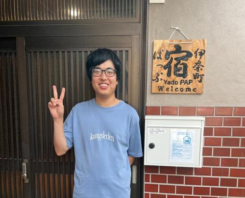a man standing in front of a door giving the peace sign at YadoPAP Ina town 宿ぱっぷ伊奈町 in Ina