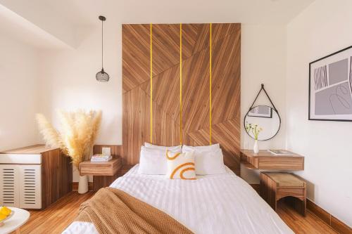 a bedroom with a bed with a wooden headboard at The Morris Central Hotel - O'TEL in Da Lat