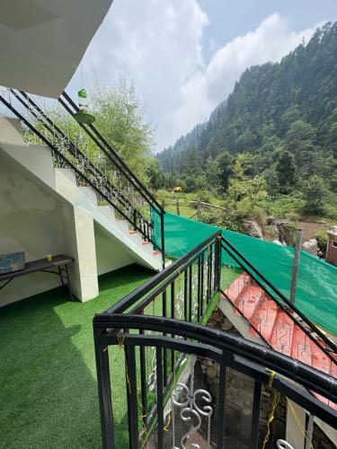 a balcony with a view of a river and mountains at The Pahadi Soul Stay and Café in Jibhi