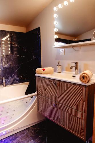 une salle de bain avec un lavabo et une baignoire dans l'établissement La Suite romantique des Chatons, à Mimizan