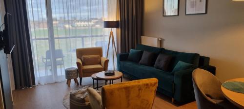un salon avec un canapé vert et une table dans l'établissement Słoneczne Sarbinowo - Apartament Marynarska 10, à Sarbinowo