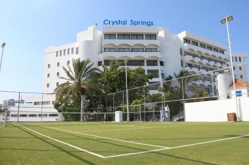 a tennis court in front of a hotel at Crystal Springs Beach Hotel in Protaras
