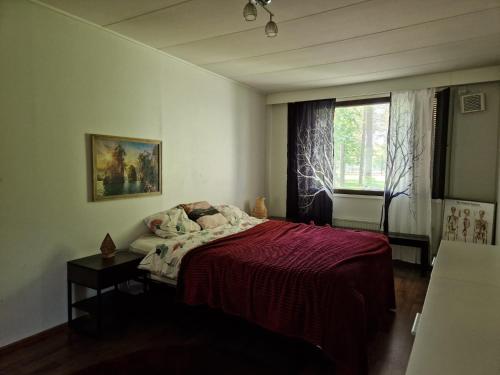 a bedroom with a bed with a red blanket and a window at House by The Lake in Oulu