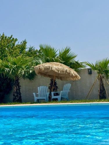 deux chaises et un parasol à côté d'une piscine dans l'établissement Cozy villa with private pool, à Piolenc