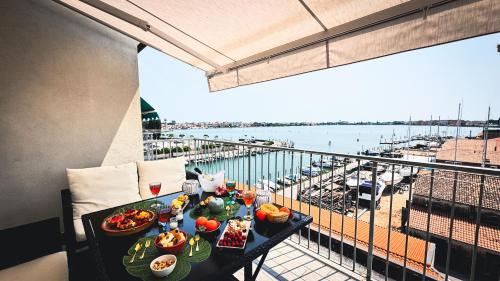 a table with food on a balcony with a view of a marina at Canal Bellavista by Ca-Sa Check in Chioggia