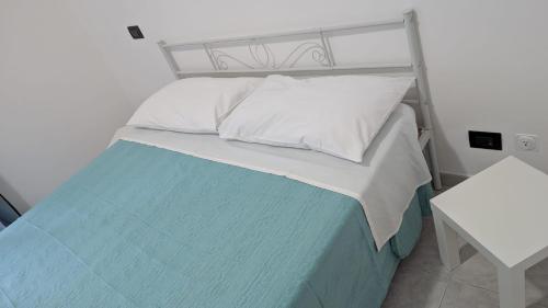 a bed with white pillows and a blue blanket at Appartamento in residence "CASA DAMIA" in Taranto