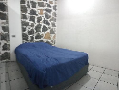a bedroom with a blue bed with a stone wall at Depto Zona UV Los Lagos Isleta 101 in Xalapa