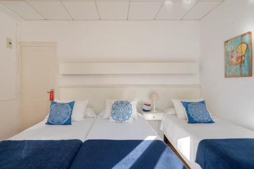 two beds with blue and white pillows in a room at La Goleta in Llança