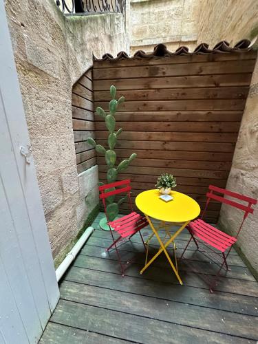 une table et des chaises sur une terrasse en bois avec un cactus dans l'établissement Superbe appartement Bordelais plein de charme et lumineux avec terrasse, à Bordeaux