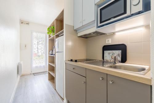 une cuisine avec un évier et un micro-ondes dans l'établissement 27 - La Perdrie - Village vacances, à Maché