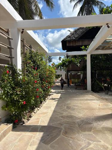 a person walking down a sidewalk next to a building at Beach Bohème in Paje