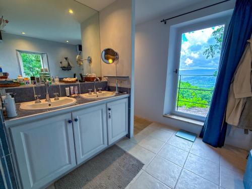 La salle de bains est pourvue de 2 lavabos et d'une grande fenêtre. dans l'établissement Mas provençal à Gordes avec piscine - Roc de Tuaran, à Gordes