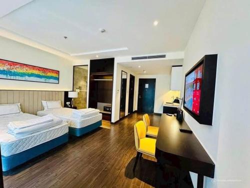 a bedroom with two beds and a desk and a tv at Sapphire S2 Hạ Long in Ha Long
