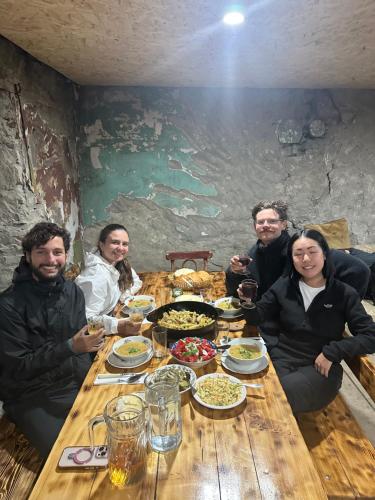 a group of people sitting around a wooden table with food at Tamazi guest house in Adishi