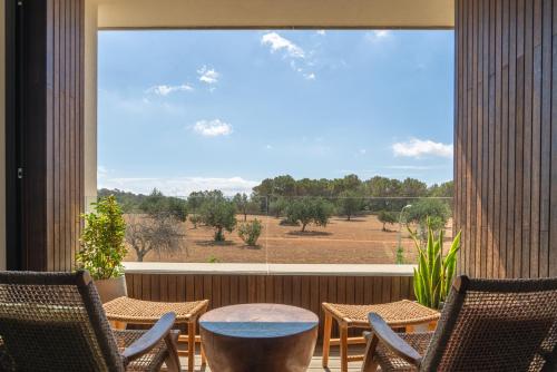 a patio with chairs and a table and a large window at Kimpton Aysla Mallorca by IHG in Santa Ponsa