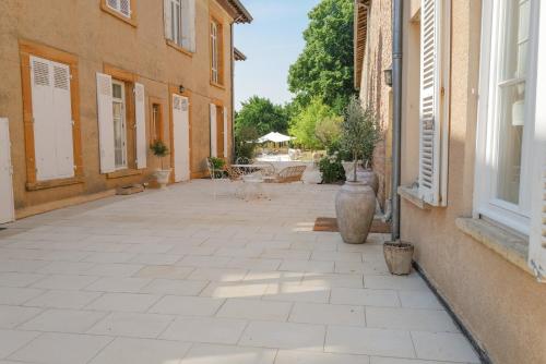 ein leerer Innenhof zwischen zwei Gebäuden mit einer Terrasse in der Unterkunft Château du Bost, 21 personnes, piscine, Beaujolais, Blacé proche Lyon in Blacé