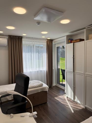 Un dormitorio con una cama y una silla y una ventana. en DHARMA Stay VILA Self check-in, en Telšiai