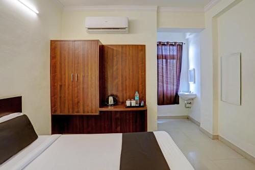 a bedroom with a bed and a wooden cabinet at Hotel O Shiridi Residency in Vidya Nagar