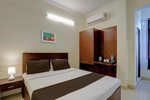a bedroom with a bed with a wooden headboard at Hotel O Shiridi Residency in Vidya Nagar