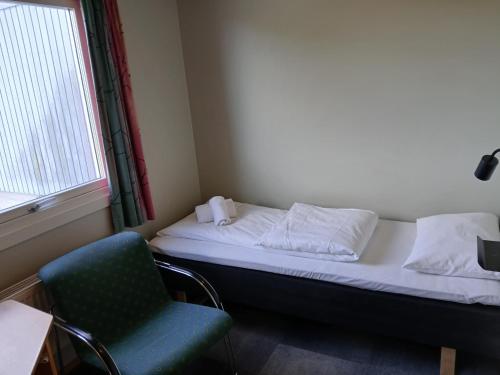 a bedroom with a bed and a chair and a window at Høk Kro & Motell AS in Sarpsborg