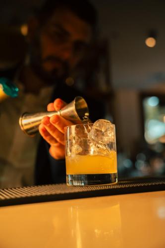 a man is pouring a drink into a glass at Kimpton Aysla Mallorca by IHG in Santa Ponsa