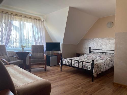 a bedroom with a bed and a couch and a chair at Pokoje Gościnne DANA in Łeba