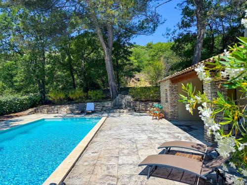 - une piscine avec 2 chaises à côté d'une maison dans l'établissement Mas provençal à Gordes avec piscine - Roc de Tuaran, à Gordes