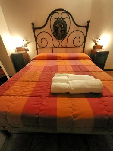 a bedroom with a bed with an orange and red blanket at Briciola di Sole b&b e ristorante in Borgo