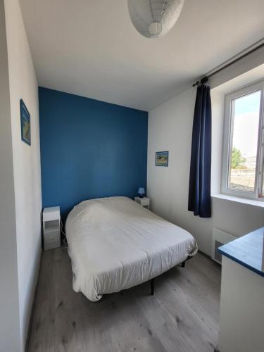 une chambre avec un lit avec un mur bleu dans l'établissement Le Villageois, à Fouesnant